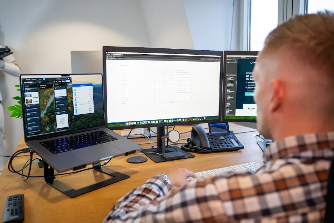 Softwareentwicklung bei Marketing Planet: Arbeitsplatz mit drei Bildschirmen